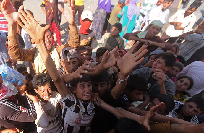 Displaced Iraqi Yazidis, who fled a jihadist onslaught on Sinjar, gather to collect bottles of water at the Bajid Kandala camp in Kurdistan's western Dohuk province, on August 13, 2014. (AFP Photo / Ahmad Al-Rubaye)