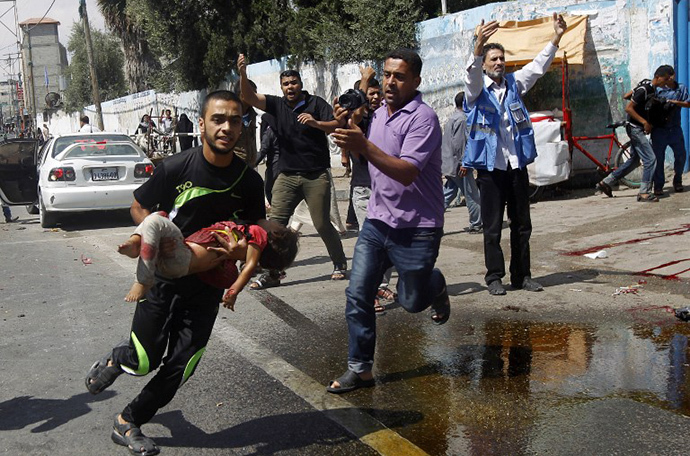 A Palestinian man carries an injured child following an Israeli military strike on a UN school in Rafah, in the southern Gaza Strip on August 3, 2014. (AFP Photo / Said Khatib)