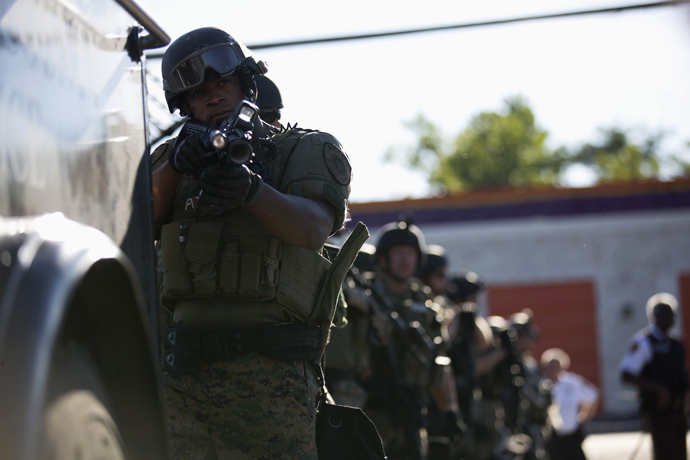 A police officer holds his riot gun while demonstrators protest the shooting death of teenager Michael Brown in Ferguson, Missouri August 13, 2014. (Reuters / Mario Anzuoni)