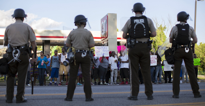 Police officers watch as demonstrators protest the death of black teenager Michael Brown in Ferguson, Missouri August 12, 2014. (Reuters / Mario Anzuoni)