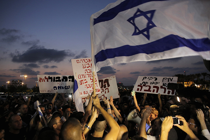 Protesters hold signs and shout slogans against the wedding of groom Mahmoud Mansour, 26, and bride Maral Malka, 23, outside a wedding hall in Rishon Lezion, near Tel Aviv August 17, 2014. (Reuters / Ammar Awad)
