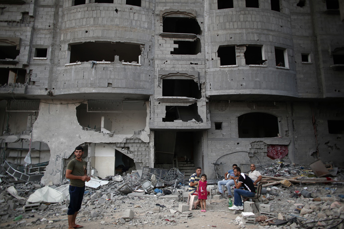 Palestinians sit in their destroyed neighbourhood in the northern Gaza Strip city of Beit Hanun, on August 18, 2014. (AFP Photo / Thomas Coex)