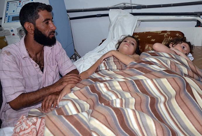 A man sits in a hospital near two children who activists say were affected by nerve gas in the Ghouta region, in the Duma neighbourhood of Damascus August 21, 2013 (Reuters / Bassam Khabieh)