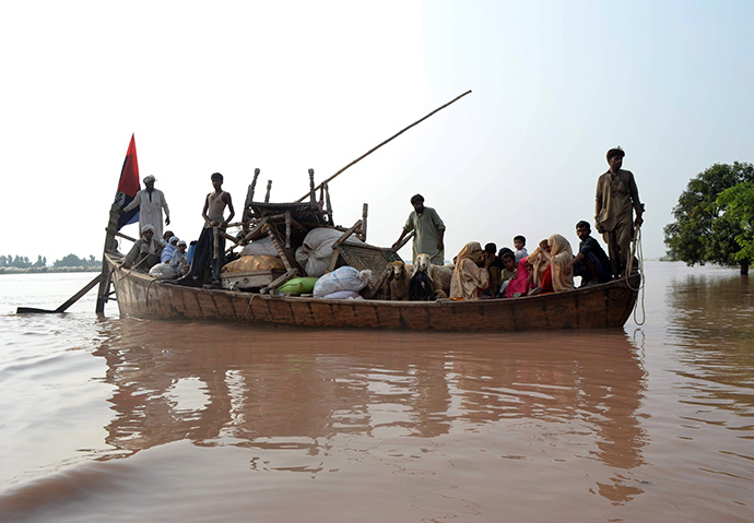 Pakistani volunteers from the Falah-i-Insaniat Foundation (FIF), which is closely linked to Islamic hardline organisation Jamaat ud Dawa (JuD), use a boat to rescue flood-affected residents from a village on the outskirts of Multan, in the central Punjab province on September 9, 2014 (AFP Photo / SS Mirza)