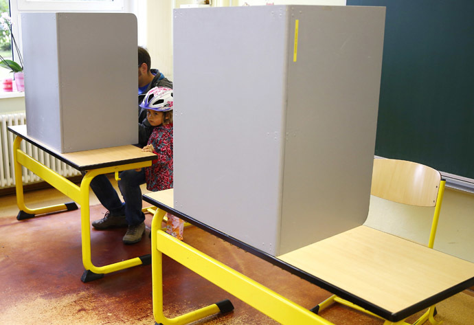 A girls stands next to her father as he casts his vote during the Thuringia state election at a polling station in a school in Erfurt September 14, 2014. (Reuters/Kai Pfaffenbach)