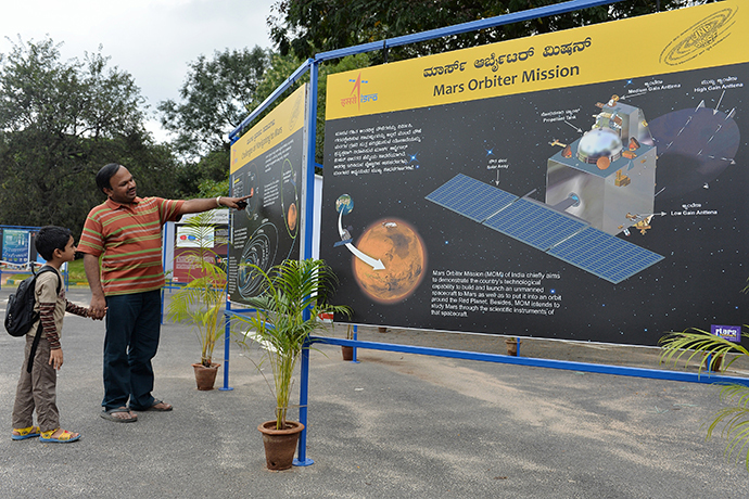 A father and son look at information about planet Mars on a poster put up at the Nehru Planetarium as a special preview on India's maiden Mars Orbiter Mission, in Bangalore on September 23, 2014. (AFP Photo / Manjunath Kiran)