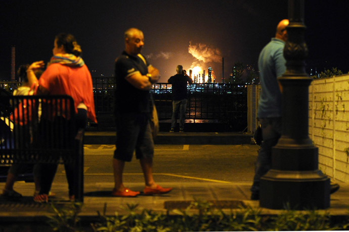 People stand as flames arise after a fire broke out at the Mediterranean Refinery of Milazzo, one of most important in southern Italy, in Milazzo, near Messina on Sicily Island on September 27, 2014. (AFP Photo/Giovanni Isolino)