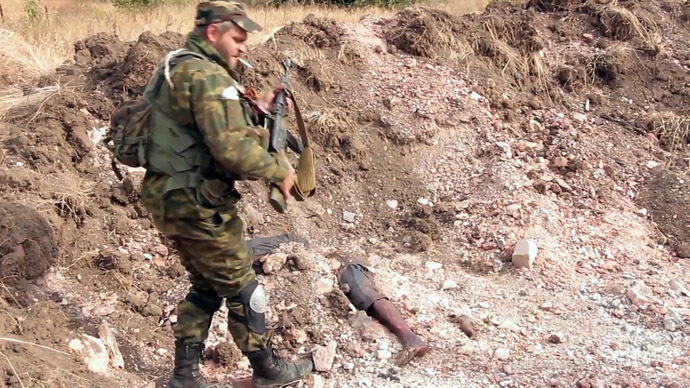 A Donetsk People's Republic militiaman is at the site of the graves of peaceful residents discovered near Mine 22 "Kommunar" outside Donetsk (still from video courtesy of the Ruptly international news agency.)