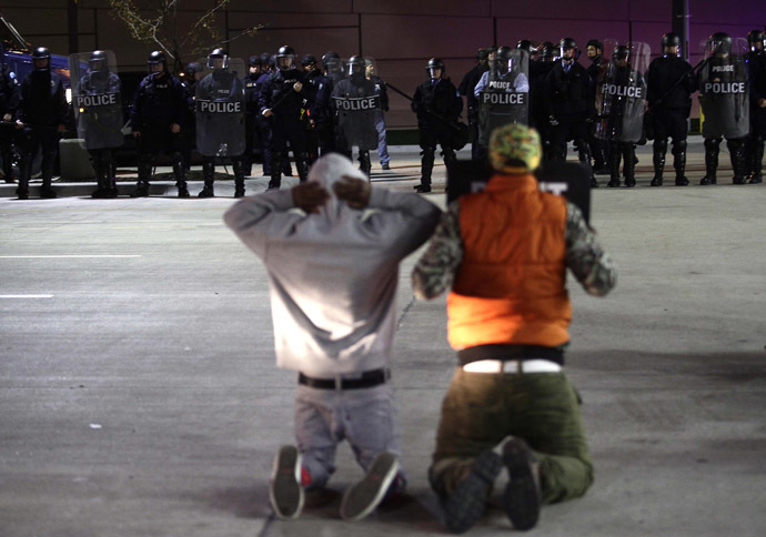 Demonstrators protesting the shooting death of Michael Brown and 18-year-old Vonderrit Myers Jr. kneel as they face police officers in riot gear at a QuikTrip convince store and gas station October, 12 2014 in St. Louis, Missouri. Civil rights organizations, protest groups and people from around the country were protesting the August 9 shooting of Brown, which involved Ferguson Police officer Darren Wilson and Meyers, who was shot and killed last week by an off duty St. Louis police officer. (AFP Photo/Joshua Lott)