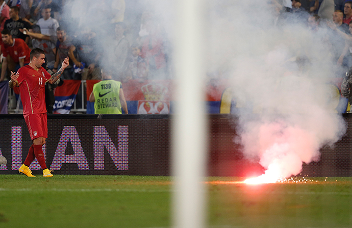Aleksandar Kolarov of Serbia reacts as flares are thrown to the pitch during their Euro 2016 Group I qualifying soccer match against Albania at the FK Partizan stadium in Belgrade October 14, 2014. (Reuters / Marko Djurica)