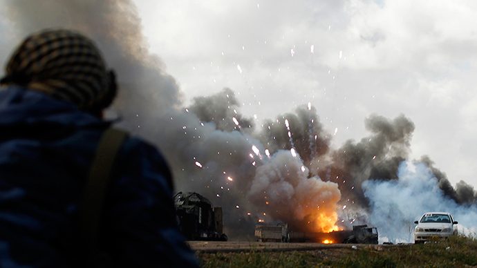ARCHIVE PHOTO: A rebel fighter looks at a burning vehicle after an air strike, along a road between Benghazi and Ajdabiyah March 20, 2011 (Reuters / Goran Tomasevic)