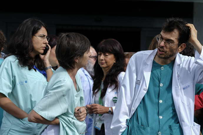 Health workers gather outside the Carlos III hospital in Madrid on October 10, 2014 where 12 people are in quarantine as a precaution following the admission of Spanish nurse Teresa Romero infected with the ebola virus. AFP Photo / Pedro Armestre