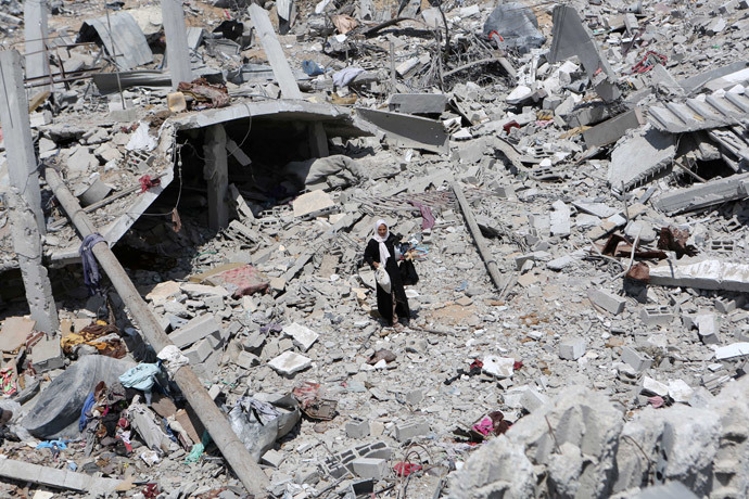 A Palestinian woman walks on the rubble of destroyed houses carrying items she collected in hers on September 13, 2014 in Khan Yunis' Khuzaa neighbourhood in the southern Gaza Strip, an area which was devastated after the Israeli bombing during the summer's fierce offensive on the Gaza Strip. (AFP Photo / Said Khatib)