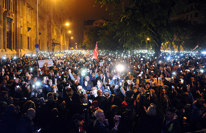 Hungarian citizens lift their mobile phones to protest against the goverment's new tax plan for the introduction of the internet tax next year in Budapest downtown on October 26, 2014. (AFP Photo/Attila Kisbenedek)