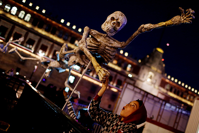 A child reacts while touching a skeleton model, which is part of an art installation to celebrate the Day of the Dead, in Zocalo Square, Mexico (Reuters / Tomas Bravo)