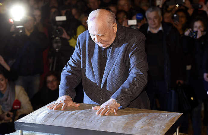 The last ruling President of the Soviet Union Mikhail Gorbachev leaves his handprints in plaster cast bolted onto an original Wall piece from former Checkpoint Charlie border crossing on November 7, 2014 in Berlin. (AFP Photo/Odd Andersen)