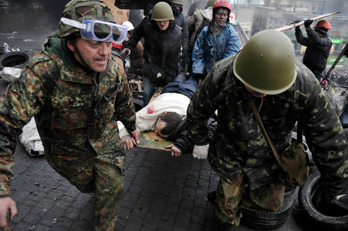 Protesters carry a wounded protester during clashes with poliÑe, after gaining new positions near the Independence square in Kiev on February 20, 2014. (AFP PHhoto / Louisa Gouliamaki)