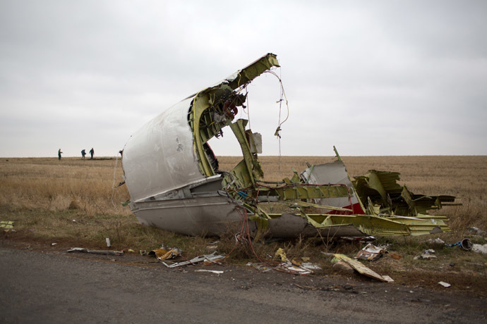 Journalists walk behind parts of the Malaysia Airlines plane Flight MH17 as Dutch investigators (unseen) arrive near at the crash site near the Grabove village in eastern Ukraine on November 11, 2014 (AFP Photo)
