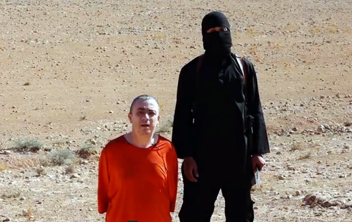 An image grab taken from a video released by the Islamic State (IS) via its "Al-Furqan » media arm on October 3, 2014 purportedly shows a masked militant (R) before the execution of British hostage Alan Henning dressed in orange and on his knees in a desert landscape. (AFP Photo / HO)