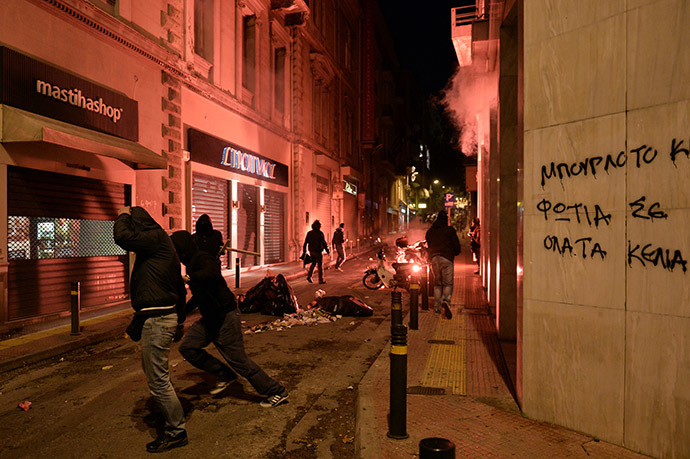 Youths throw stones and flares toward riot police on December 6, 2014 during clashes at the end of a youth protest to commemorate the six-year anniversary of the fatal shooting of teenager Alexis Grigoropoulos by a police officer, an event that plunged Greece into weeks of rioting. (AFP Photo/Louisa Gouliamaki)