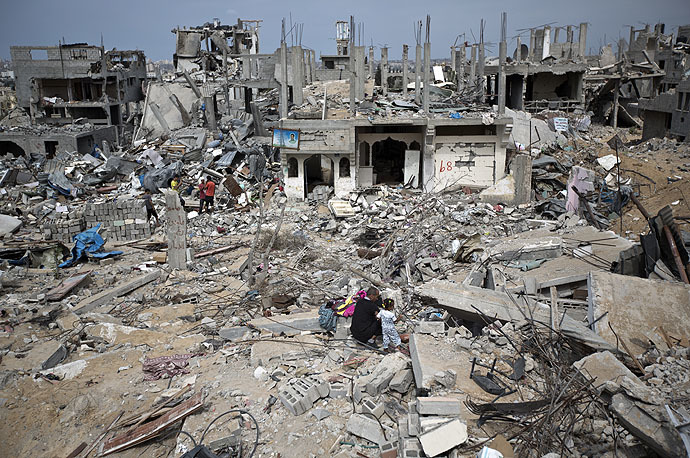 Palestinians walk amidst destroyed buildings in al-Tufah, east of Gaza City on October 11, 2014 (AFP Photo/Mahmud Hamas)