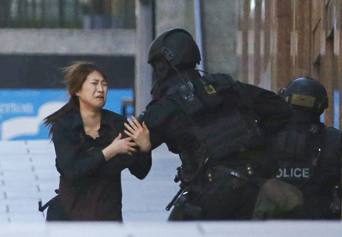 A hostage runs towards a police officer outside Lindt cafe, where other hostages are being held, in Martin Place in central Sydney December 15, 2014. (Reuters/Jason Reed)