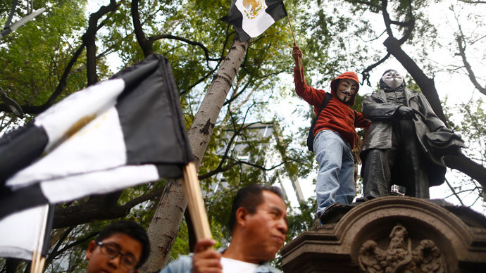 An activist wearing a Guy Fawkes mask is seen on a monument during a march to demand justice for the 43 missing students from Ayotzinapa Teacher Training in Mexico City December 26, 2014. (Reuters / Edgard Garrido)