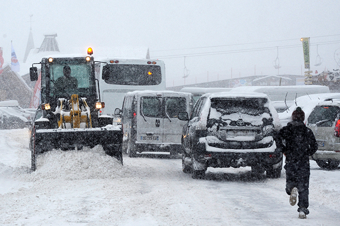 A man uses a snow plow to clean the road as vehicles drive past on December 27, 2014 on the road to the Les Saisies ski resort in Savoie, central-eastern France. (AFP Photo / Jean-Pierre Clatot)