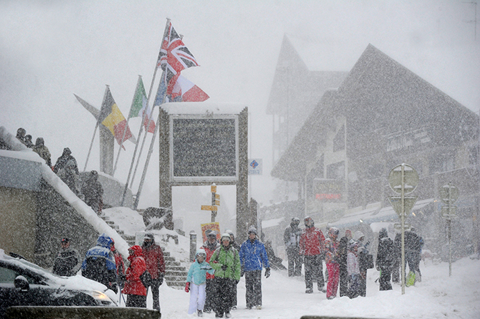 People walk at the Les Saisies ski resort in Savoie, central-eastern France, as snow falls on December 27, 2014. (AFP Photo / Jean-Pierre Clatot)