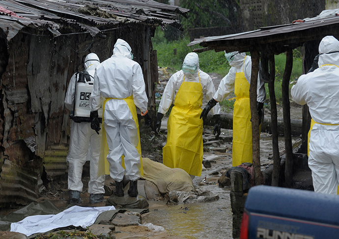 Health workers wearing protective clothing prepare to carry an abandoned dead body presenting with Ebola symptoms at Duwala market in Monrovia August 17, 2014. (Reuters / 2Tango)