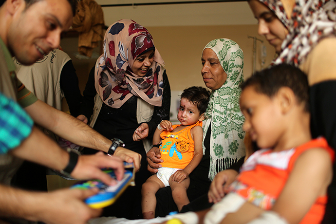 Palestinian boy Mohammed Wahdan (C), whom medics said was wounded in Israeli shelling, receives psychological care at Shifa hospital in Gaza City (Reuters / Mohammed Salem)