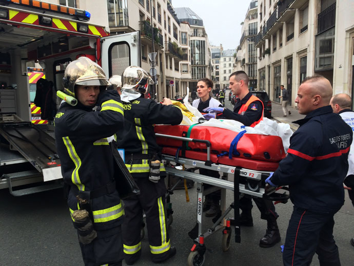 Firefighters carry an injured man on a stretcher in front of the offices of the French satirical newspaper Charlie Hebdo in Paris on January 7, 2015, after armed gunmen stormed the offices leaving at least one dead according to a police source and "six seriously injured" police officers according to City Hall. (AFP Photo)