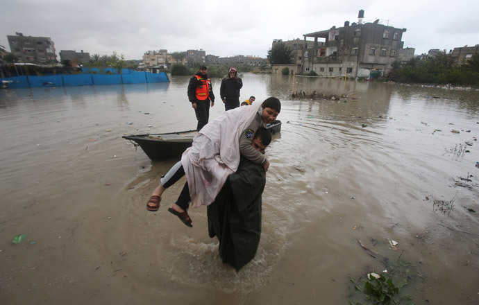 A member of Palestinian Civil Defence carries a boy after he was evacuated from his family's house which was flooded by heavy rain in Rafah in the southern Gaza Strip January 9, 2015. (Reuters / Ibraheem Abu Mustafa)