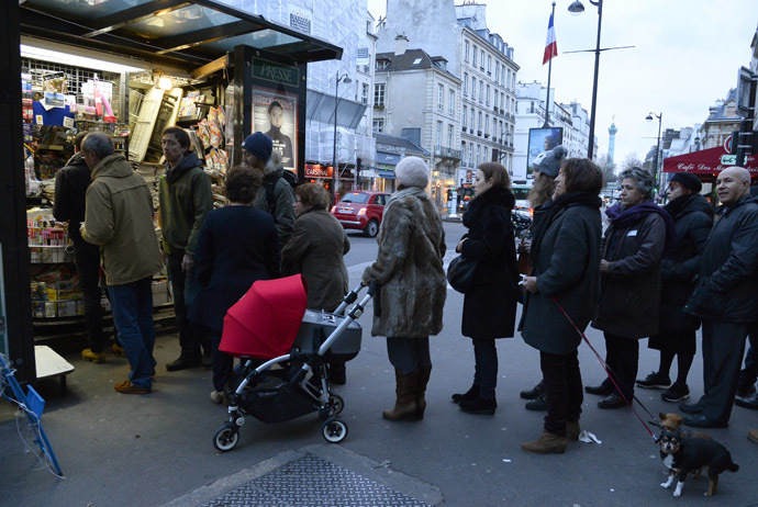 People wait outside a newsagents kiosk in Paris on January 14, 2015 as the latest edition of French satirical magazine Charlie Hebdo went on sale. (AFP Photo/Bertrand Guay)