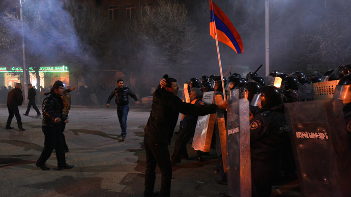 A man holds an Armenian flag up as protesters clash with police during a demonstration near the Russian Consulate General in Gyumri, north-western Armenia, on January 15, 2015.(AFP Photo / Karen Minasyan)