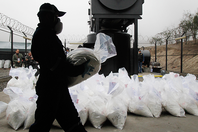 An anti-narcotics worker carries a bag containing the cocaine seized last week near Trujillo, during its incineration at a special operation police headquarters, in Lima, Peru (Reuters / Enrique Castro-Mendivil)