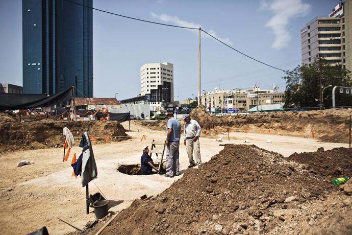A worker for the Israel Antiquities Authority (IAA) stands in a pit at an archaeological dig in a future construction site in Tel Aviv, where fragments of ancient basins were unearthed, March 29, 2015. (Reuters / Nir Elias)