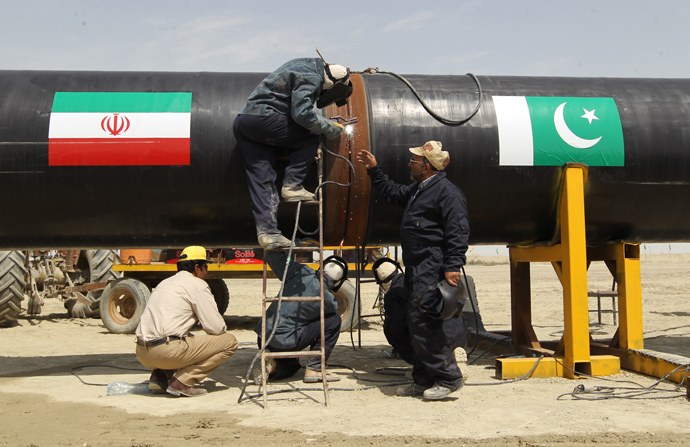 Iranians work on a section of a pipeline (on with are sticked Iranian and Pakistanese national flags) after the project was launched during a ceremony with presidents of Iran and Pakistan on March 11, 2013 in the Iranian border city of Chah Bahar (AFP Photo / Atta Kenare)