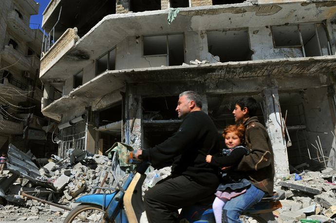 Syrian man drives his motorcycle past damaged buildings in Maarat al-Numan, in the northwestern province of Idlib (AFP Photo / Bulent Kilic)