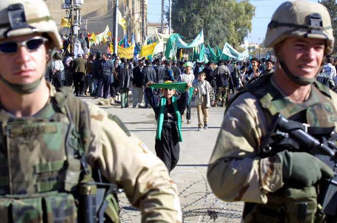 An Iraqi Kurdish boy holds up a green flag behind US soldiers during a demonstration in Kirkuk, 255 kilometres (155 miles) north of Baghdad.(AFP Photo / Abdelhak Senna)