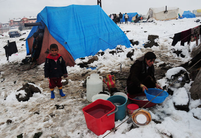 A child watches a woman washing a bassin at the Syrian refugee camp 5km from Diyarbakir, on the the way between Diyarbakir and Mardin, after snowfall, on January 9, 2013.(AFP Photo / Stringer)