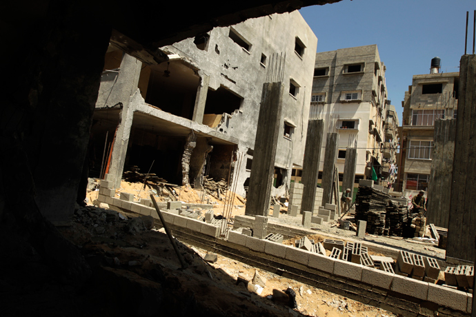 Palestinian workers rebuild a house in Gaza City in which Mohammed al-Dallu, a Hamas policeman described by the Israeli army as a terrorist, was killed along with nine other members of his family and two neighbours during Israel's last November Gaza campaign, on April 15, 2013 (AFP Photo / Mohammed Abed)