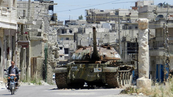 Man riding his motorbike past a burnt out Syrian Army tank in Rastan, in the central Homs province.(AFP Photo / Shaam News Network)