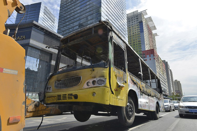 This picture taken on August 5, 2013 shows the shell of a burnt out bus being towed by a rescue vehicle along a street in Urumqi in northwest China's Xinjiang Uygur Autonomous Region (AFP Photo)