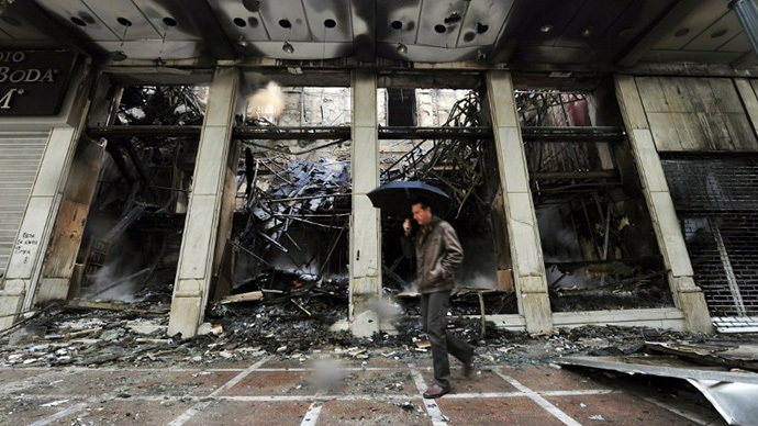 A man walks past a burned store in central Athens (AFP Photo / Louisa Gouliamaki)