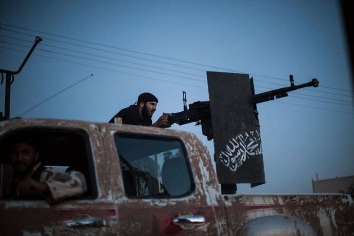 A member of the Islamist Syrian opposition group Ahrar al-Sham fires against a position of the Committees for the Protection of the Kurdish People (YPG), a militia set up to protect Kurdish areas in Syria from opposing forces, during clashes in the countryside of the northern Syrian Raqqa province on August 25, 2013. (AFP Photo / Alice Martins)