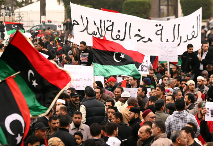 Libyans wave their new national flag and hold a banner that reads in Arabic "Federalism is against Islamic laws" during a rally in Tripoli's Martyrs' Square on March 9, 2012 against federalism after tribal and political leaders declared Libya's oil-rich eastern region of Cyrenaica as autonomous, raising fears the country may break up in the wake of Moamer Kadhafi's downfall. (AFP Photo)