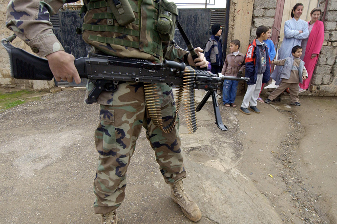 Iraqi children look at US soldiers from the 1st battalion, 22nd Regiment of the 4th Infantry Division conducting a foot-patrol along a street of former Iraqi dictator Saddam Hussein's hometown Tikrit, 180 Kilometers (110 miles) north of Iraqi capital Baghdad, 27 December 2003 (AFP Photo / Jewel Samad)