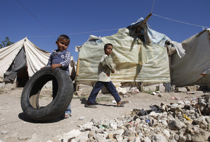 A Palestinian refugee boy from Syria plays with a tyre as another boy walks past tents at Ain al-Helweh Palestinian refugee camp near the port-city of Sidon, southern Lebanon (Reuters/Ali Hashisho)