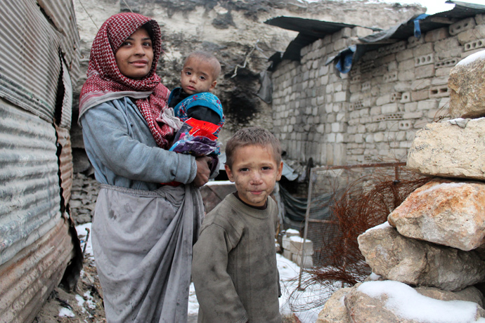 Snow covers the ground as a family stands outside their make shift home, after their house was allegedly detroyed in fighting between the rebels and pro-governemt forces, in the northern Syrian city of Aleppo (AFP Photo / Mohammed Al-Khatieb)